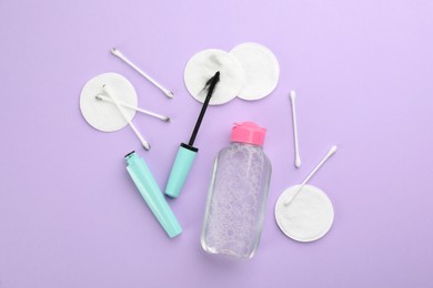 Photo of Dirty cotton pads, swabs, mascara and micellar cleansing water on lilac background, flat lay