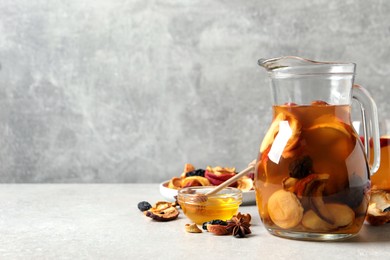 Photo of Delicious compote with dried fruits and ingredients on light grey table, space for text