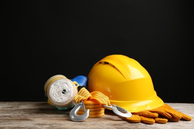 Photo of Different safety equipment on wooden table against black background. Space for text