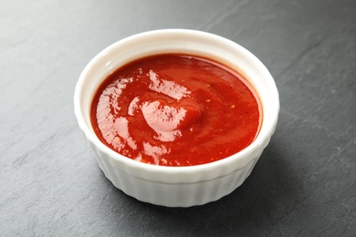 Photo of Bowl of tasty tomato sauce on grey table