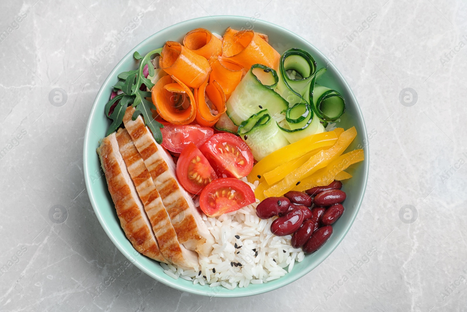 Photo of Tasty rice with beans and chicken meat on light grey marble table, top view