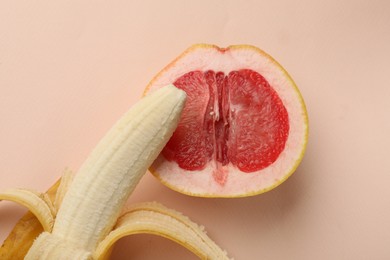 Photo of Banana and half of grapefruit on beige background, top view. Sex concept