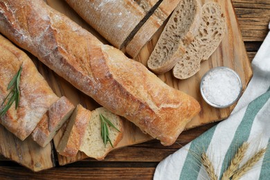 Photo of Crispy fresh ciabatta and baguettes on wooden table, flat lay