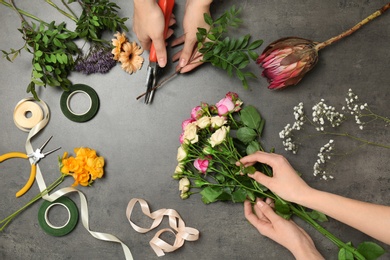 Female florists making beautiful bouquet at table, top view