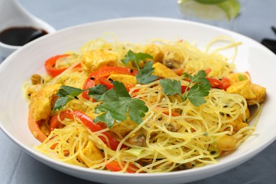 Photo of Stir-fry. Delicious cooked noodles with chicken and vegetables in bowl on gray table, closeup