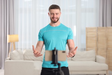 Trainer streaming online fitness lesson with phone at home