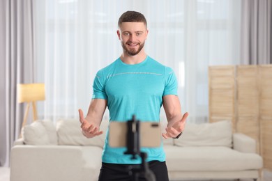 Photo of Trainer streaming online fitness lesson with phone at home