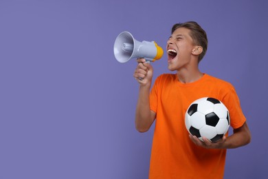 Photo of Sports fan with soccer ball shouting in megaphone on purple background. Space for text