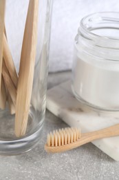 Photo of Bamboo toothbrushes and jar of baking soda on light grey table, closeup
