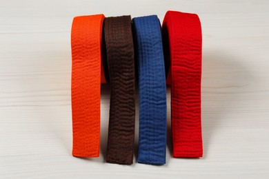 Photo of Colorful karate belts on wooden background. Martial arts uniform