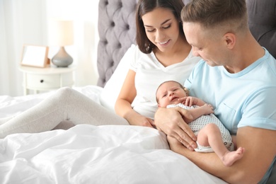 Photo of Happy couple with their newborn baby on bed