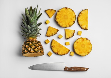 Composition with raw cut pineapple and knife on white background, top view