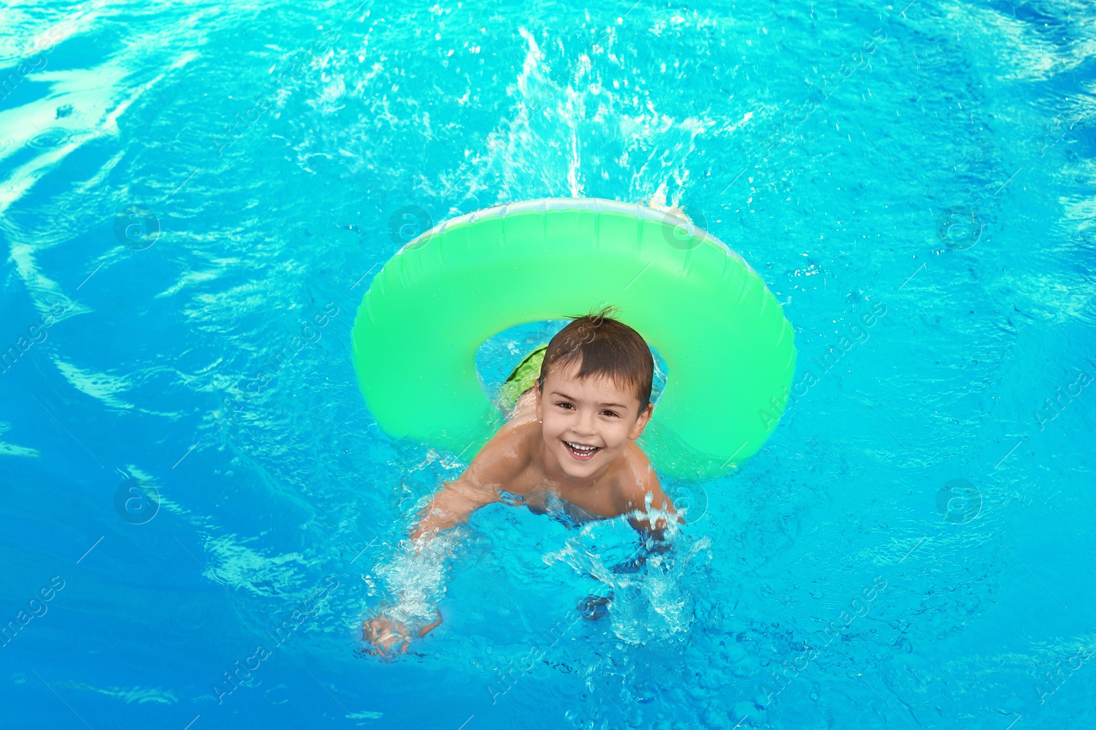Photo of Little child with inflatable ring in outdoor swimming pool. Dangerous situation