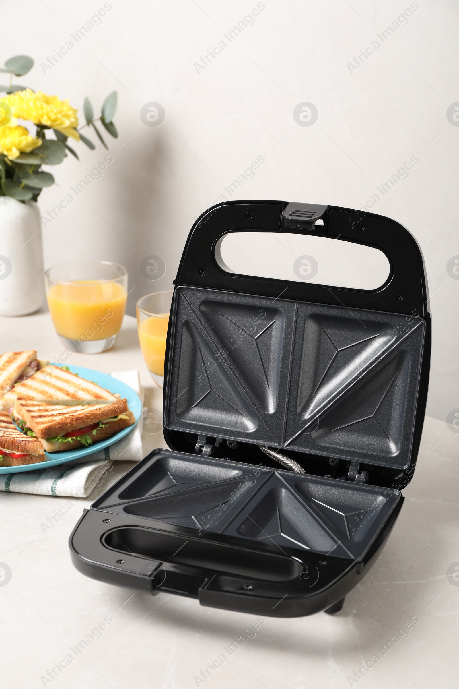 Photo of Modern grill maker and sandwiches on white table