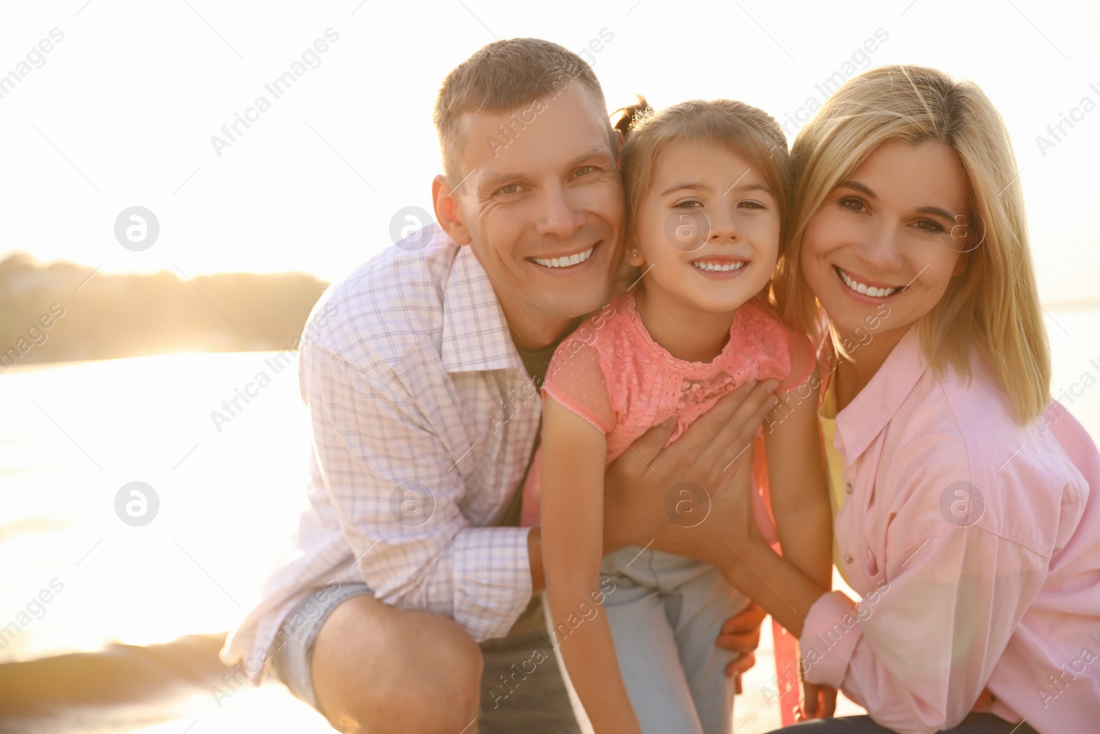 Photo of Happy parents with their child on beach. Spending time in nature