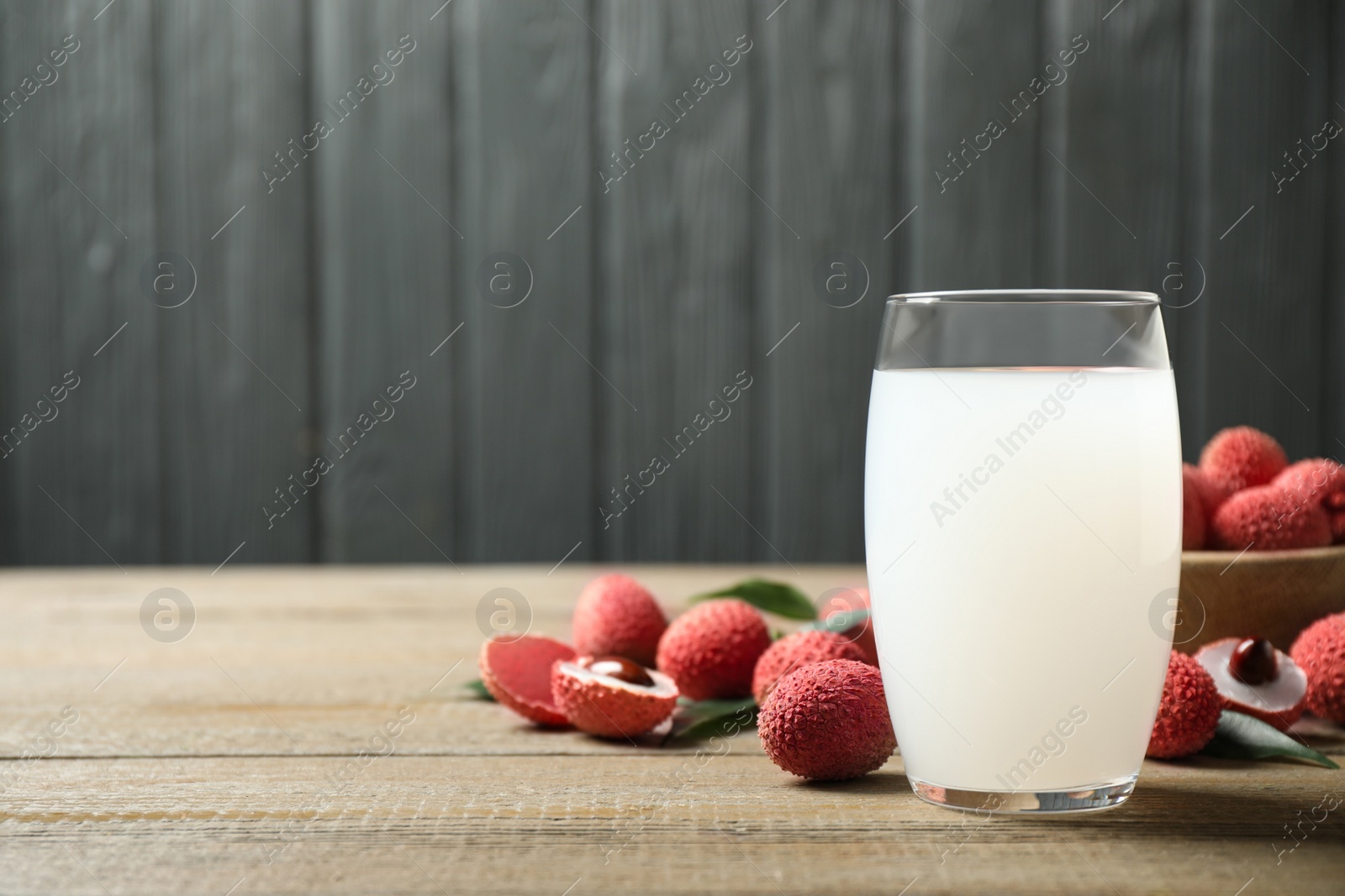 Photo of Lychee juice and fresh fruits on wooden table. Space for text