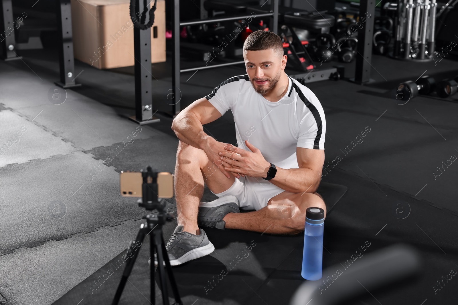 Photo of Trainer streaming online workout with phone at gym