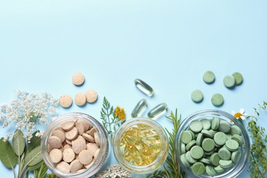 Photo of Different pills, herbs and flowers on light blue background, flat lay with space for text. Dietary supplements