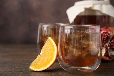 Tasty kombucha with ice cubes and fruits on wooden table