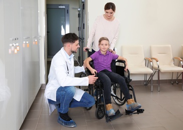 Photo of Doctor with woman and her child in wheelchair at hospital