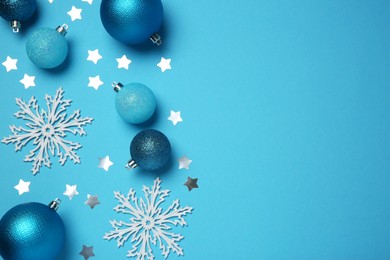 Christmas balls, decorative snowflakes and confetti on light blue background, flat lay. Space for text