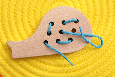 Motor skills development. Wooden lacing toy on yellow mat, top view