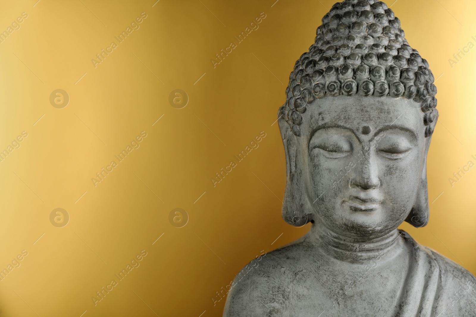 Photo of Buddha statue on golden background, closeup. Space for text