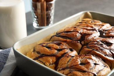 Photo of Baking dish with cinnamon rolls on table, closeup