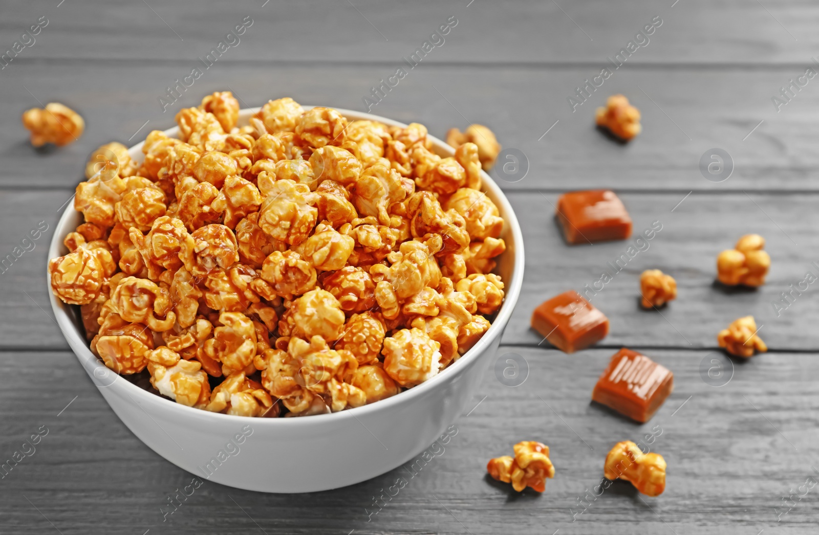 Photo of Delicious popcorn with caramel in bowl on table