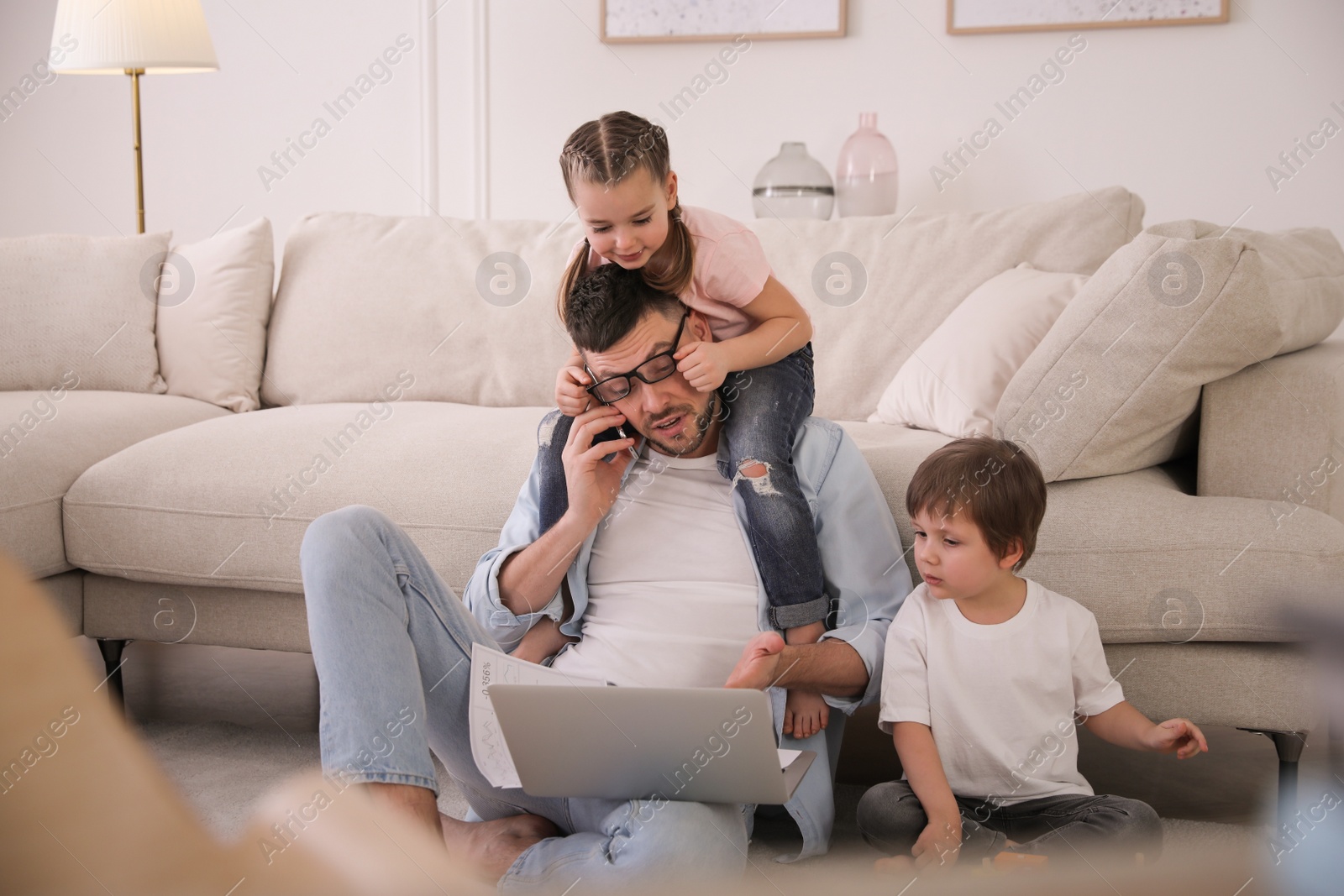 Photo of Overwhelmed man combining parenting and work at home