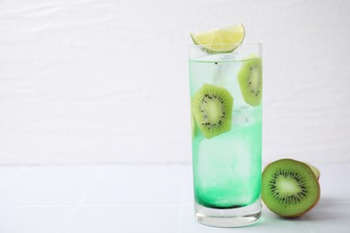 Photo of Glass of refreshing drink and cut kiwi on white table. Space for text