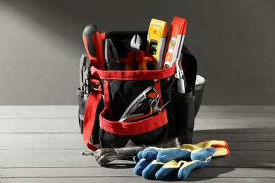 Photo of Bag with different tools for repair and protective gloves on wooden table