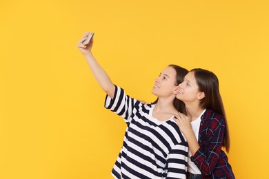Photo of Teenage girls taking selfie on orange background