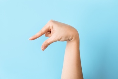 Photo of Woman showing Q letter on color background, closeup. Sign language