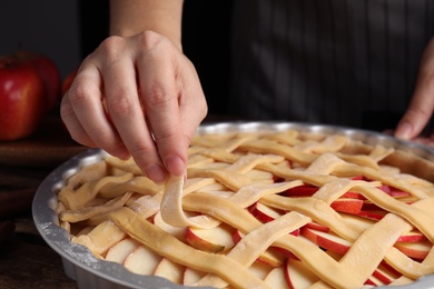 Photo of Woman making lattice top for traditional English apple pie, closeup