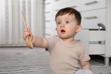 Photo of Cute little boy with wooden spoon at home