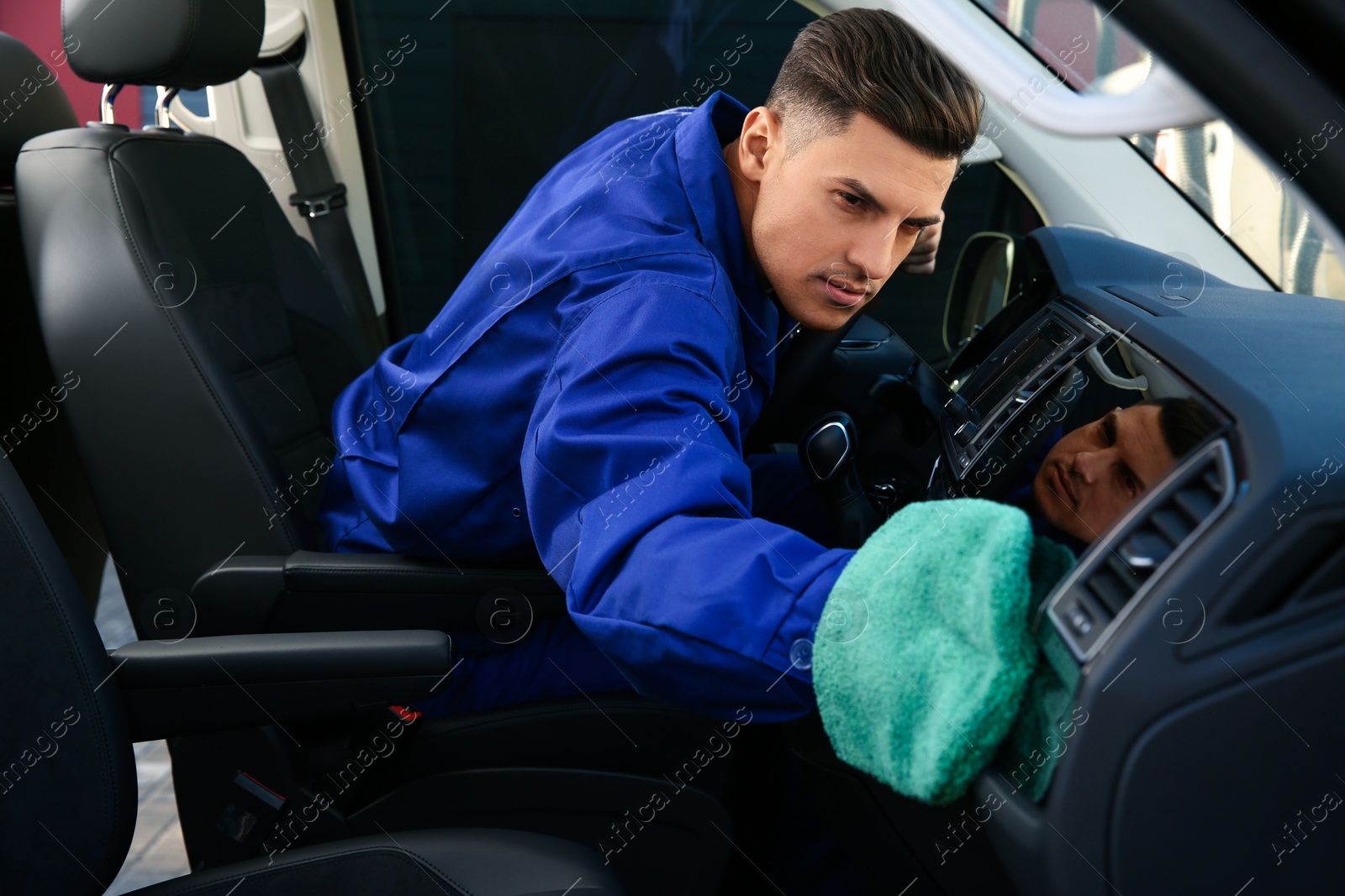 Photo of Car wash worker cleaning modern automobile interior