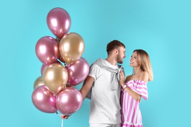 Young couple with air balloons on color background