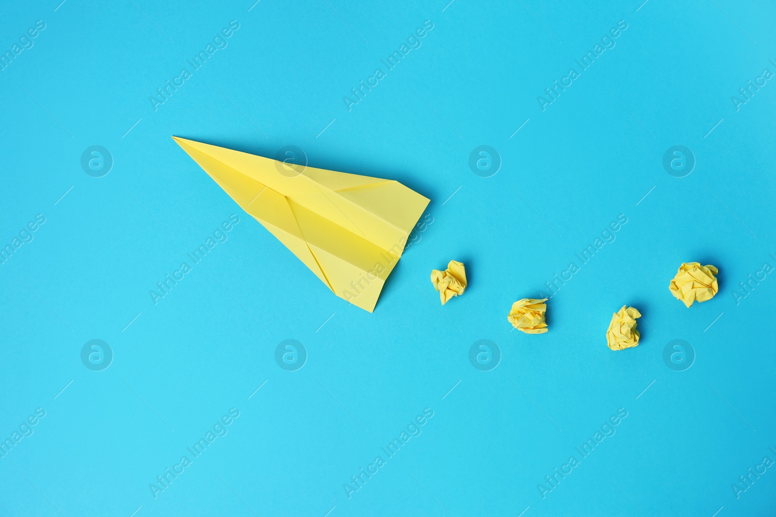 Photo of Handmade plane and many crumpled pieces of paper on light blue background, flat lay