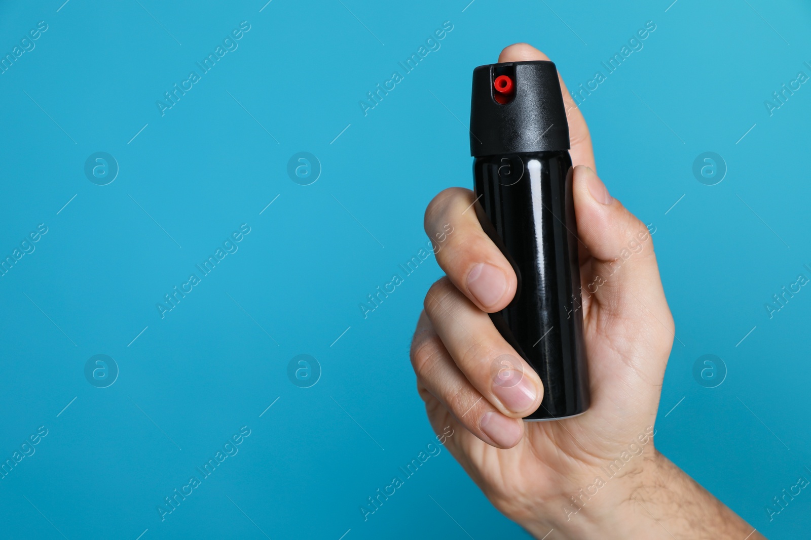 Photo of Man using pepper spray on turquoise background, closeup. Space for text