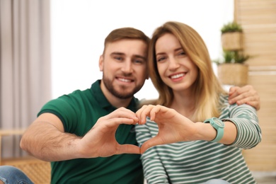 Photo of Happy couple making heart with their hands indoors