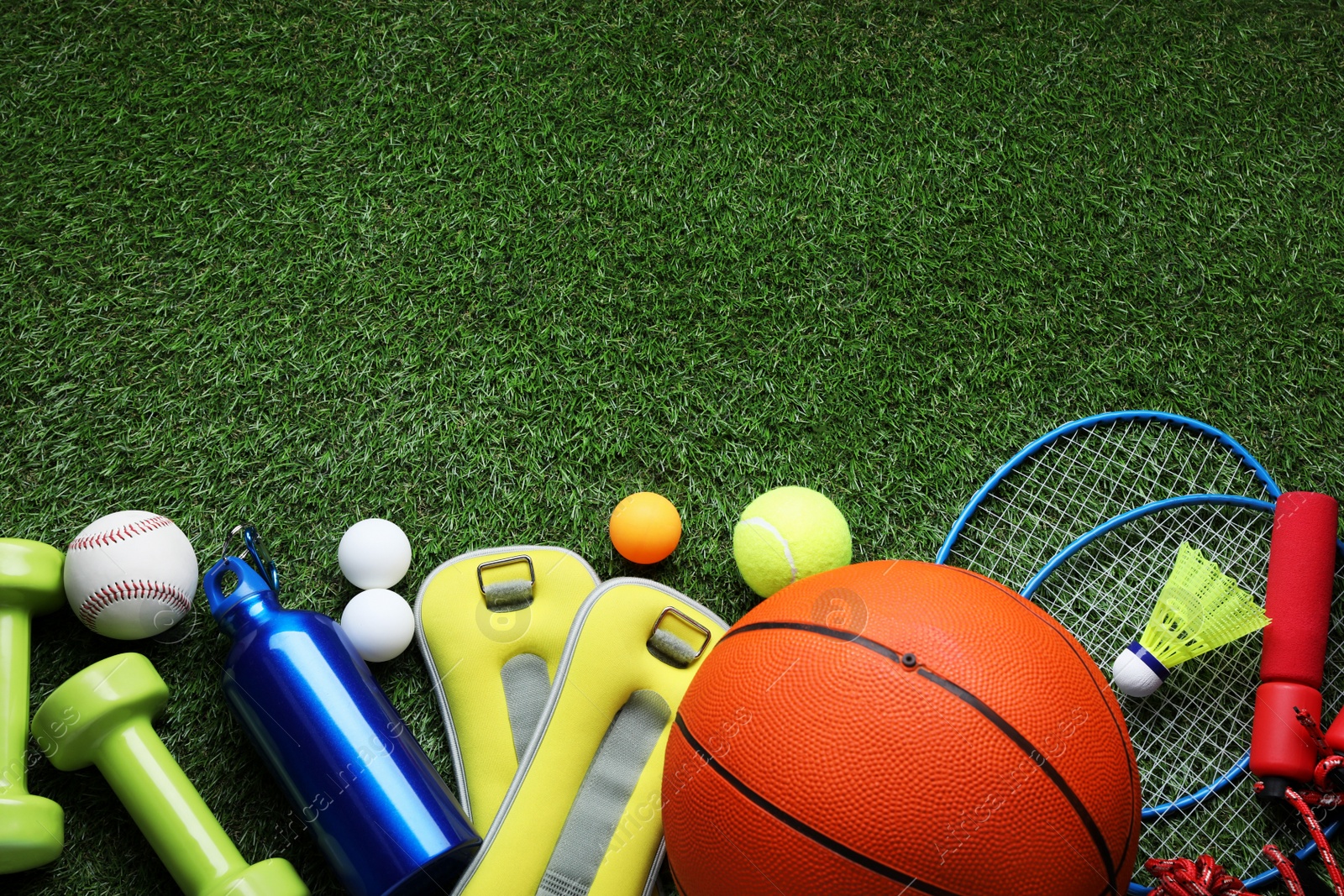 Photo of Set of different colorful sports equipment on green grass, flat lay. Space for text