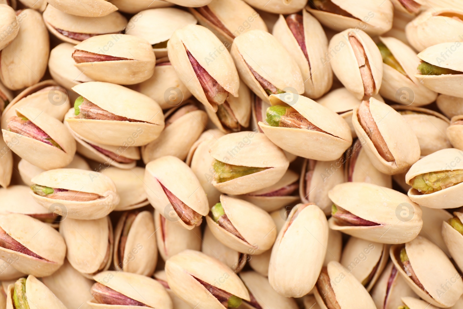 Photo of Tasty unpeeled pistachios as background, top view