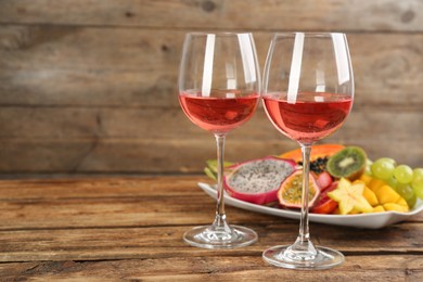 Delicious exotic fruits and wine on wooden table. Space for text