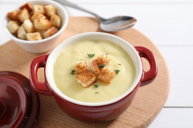 Photo of Tasty potato soup with croutons and rosemary in ceramic pot on white table, closeup