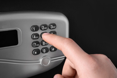 Man opening black steel safe with electronic lock, closeup