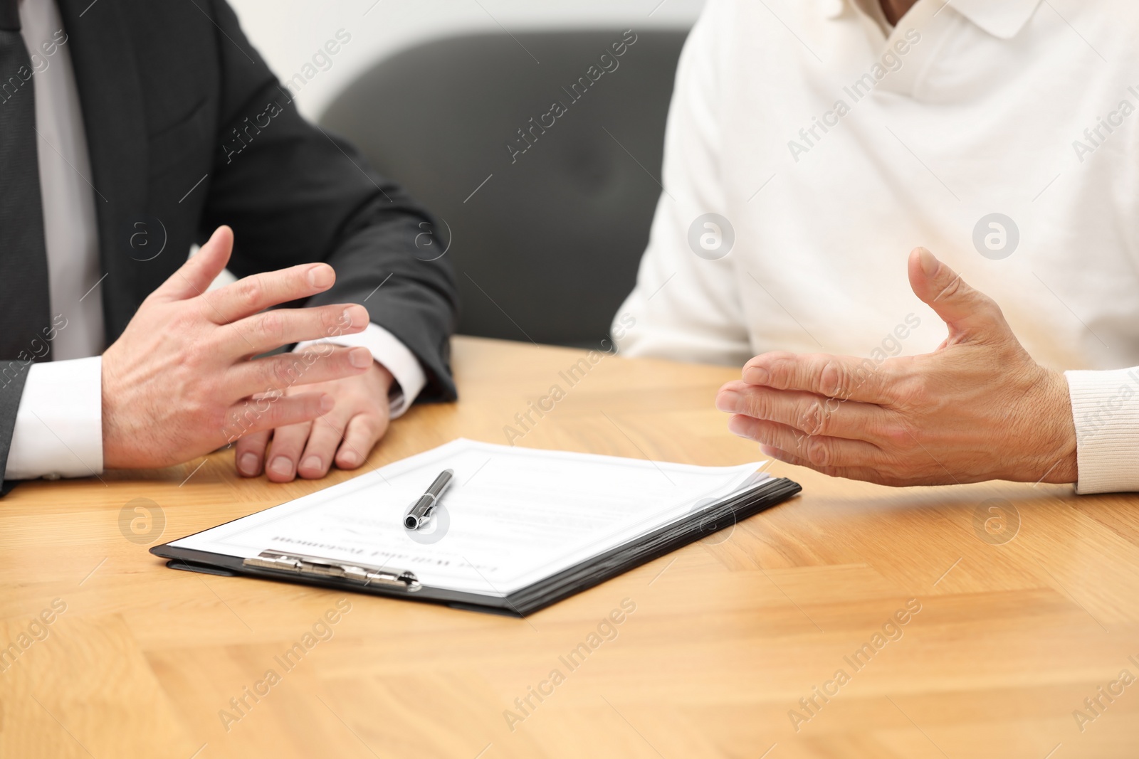 Photo of Notary consulting senior man about Last Will and Testament at wooden table indoors, closeup