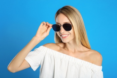 Beautiful woman in stylish sunglasses on light blue background