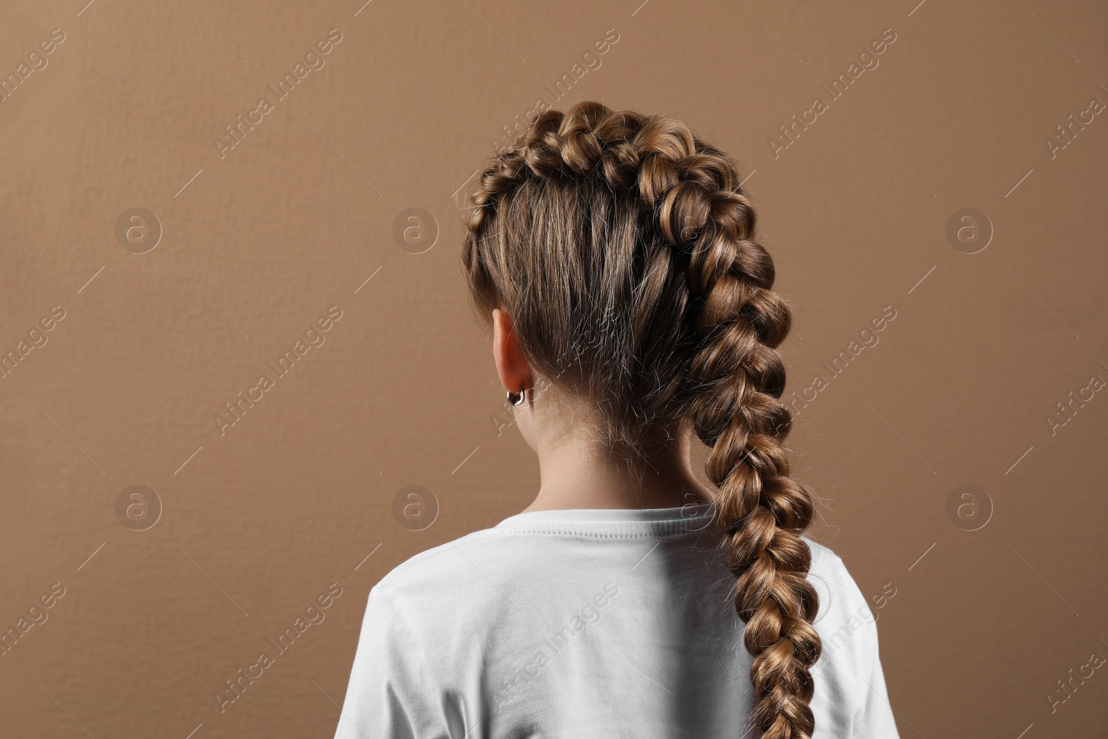 Photo of Little girl with braided hair on light brown background, back view