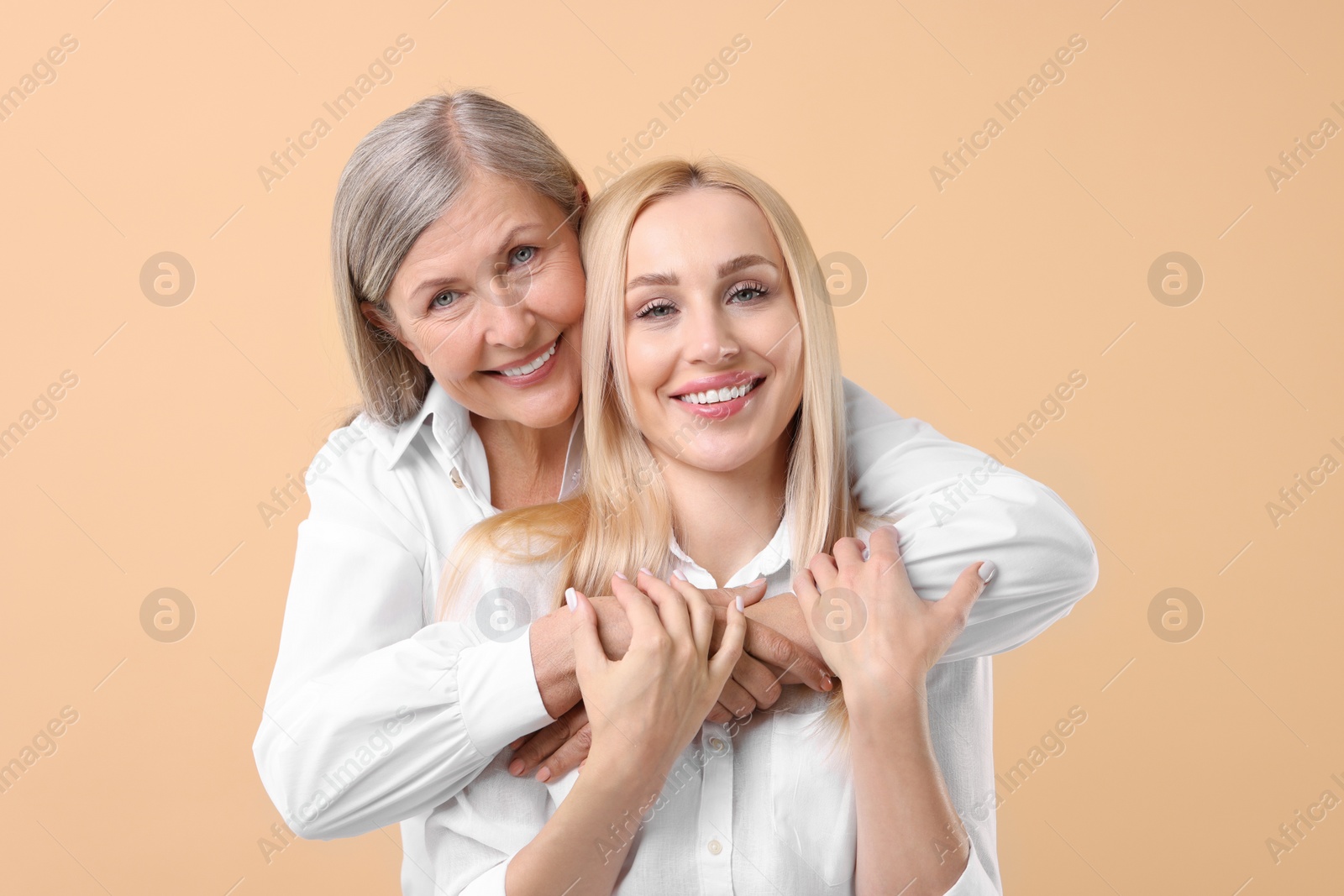 Photo of Family portrait of young woman and her mother on beige background